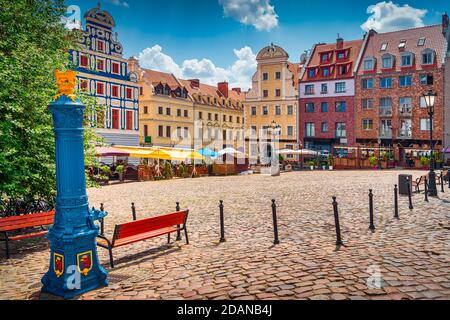 Traditional blue water pump with gryphon head crest from Szczecin city emblem and old town square in background. Gryphon is Stettin emblem since 1360 Stock Photo