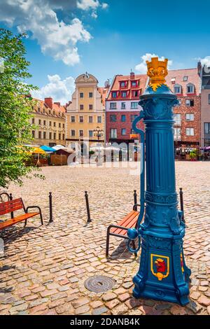 Traditional blue water pump with gryphon head crest from Szczecin city emblem and old town square in background. Gryphon is Stettin emblem since 1360 Stock Photo