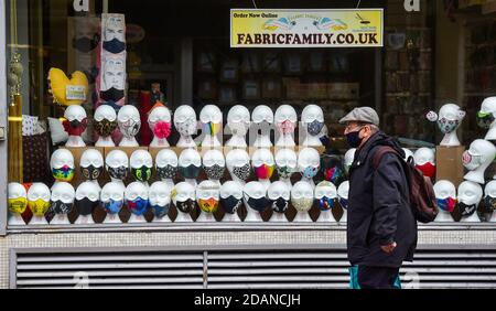 Brighton UK 14th November 2020 - A man wearing a face covering passes a closed shop selling masks in Brighton as the shopping area of the city remains quiet due to the latest Coronavirus COVID-19 lockdown restrictions in England : Credit Simon Dack / Alamy Live News Stock Photo