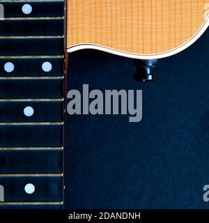 Partial aerial view of the neck and body of a wooden acoustic guitar isolated on a black background. Stock Photo