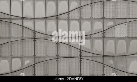 A black and white image of a modern panelled and riveted tiled wall, with curved lines which create a wave effect. Stock Photo