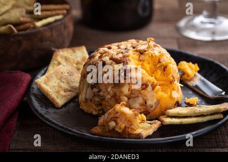 Cheddar cheese ball and crackers on a black plate Stock Photo