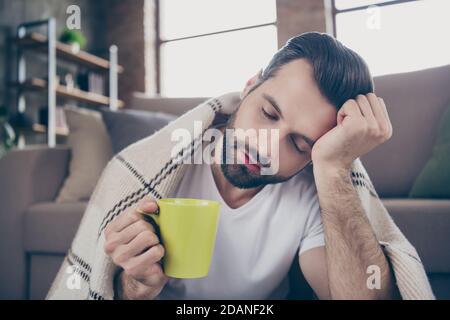 Close-up portrait of his he nice attractive tired exhausted overworked guy feeling bad drinking remedy cure herbal tea suffering symptom syndrome at Stock Photo