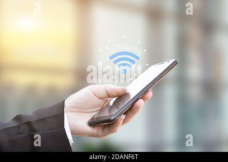 Hand holding using mobile smartphone with wifi icon. Idea for business communication social network. Stock Photo