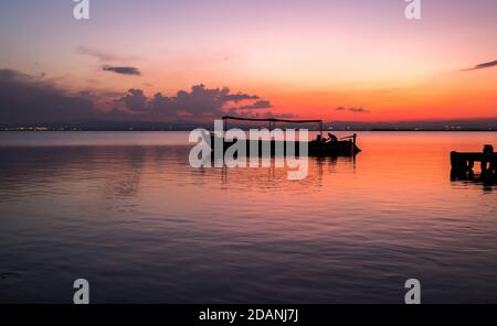 Sunset pier Albufera Valencia tourist ride boat reflections in the lake Natural Park Spain. Stock Photo