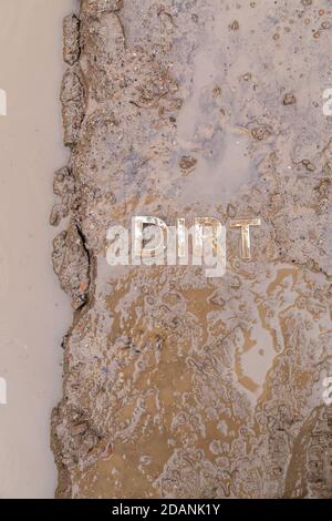 the word mud imprinted in wet dirt road surface and puddle - close-up with selective focus in flat lay perspective. Stock Photo