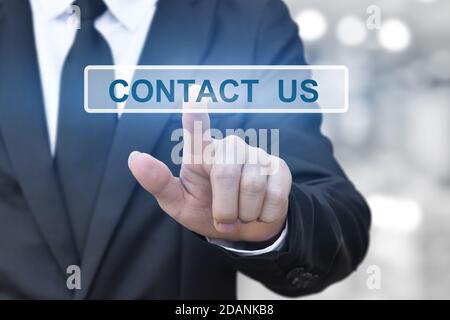 businessman hand pressing a contact us button on blur bokeh lights background. Stock Photo