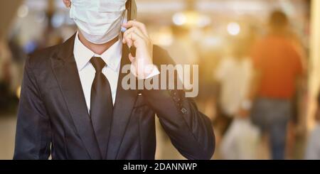 Close-up of businessman wearing face mask in black suit, Using smartphone to talking. Stock Photo