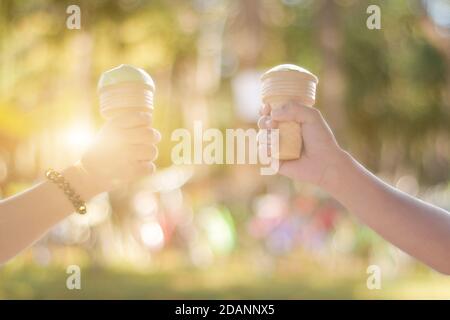 Two hand holding ice-cream cone in summer day on vacation. Stock Photo