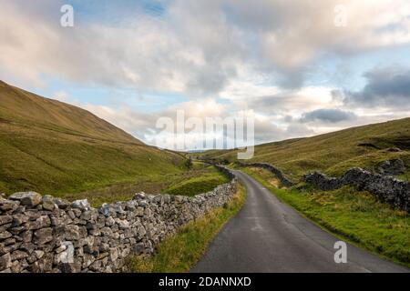 UK landscape: View looking north up the picturesque country lane of Barbondale Road, lined with drystone wall, Cumbria - Yorkshire Dales National Park Stock Photo