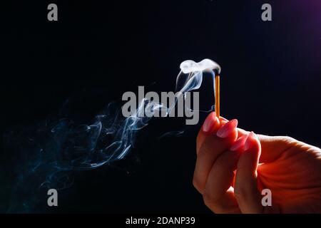 Hand holding match stick on black background Stock Photo