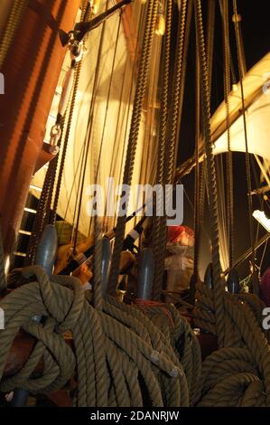 'Middle watch'traditional watch system with watchman on deck among belaying pins & hemp rope on The Prince William a square-rigged brig, training ship Stock Photo