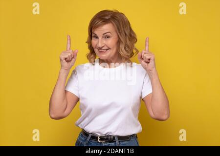 Senior smiling woman pointing up giving advice. Stock Photo