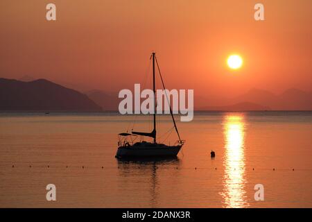 Beautiful sunrise in Aegean sea with boat and mountains, Turunc beach, Turkey Stock Photo