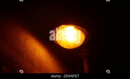 Old broken street lantern next to a house wall giving a feeling of loneliness and melancholy Stock Photo