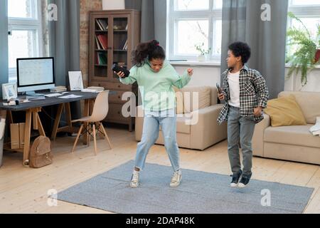 Two cute mixed-race siblings in casualwear having fun on the carpet at home Stock Photo