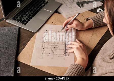 Hands of young female engineer or architect with ruler and pen making sketch Stock Photo