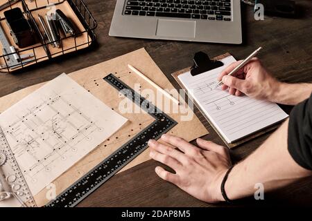 Hands of young male engineer or architect with ruler and pen making sketch Stock Photo