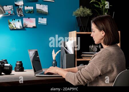 Contemporary young female designer or photographer using laptop in studio Stock Photo