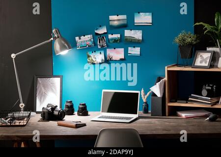 Workplace of photographer with photos of nature on blue board in front of table Stock Photo