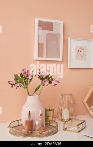 Two pictures in frames on wall by table with flowers in vase and other stuff Stock Photo