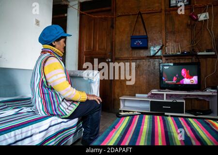 (201114) -- KUNMING, Nov. 14, 2020 (Xinhua) -- An elderly woman of the Derung ethnic group watches TV at her home in Kongdang Village in Dulongjiang Township, southwest China's Yunnan Province, Nov. 1, 2020. Southwest China's Yunnan Province, which had the country's largest remaining poor population at the end of last year, has eradicated absolute poverty, officials said on Saturday. The last nine counties in the province were delisted from the poverty-stricken county list, which meant all its 88 poverty-stricken counties have shaken off poverty, said Huang Yunbo, director of the provincial Stock Photo