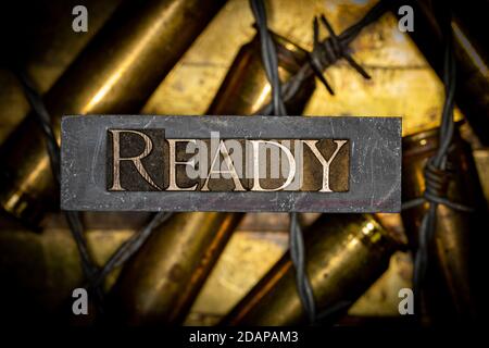 Ready text message over 50 caliber rifle cartridges on vintage textured grunge copper background lined with barbed wire Stock Photo