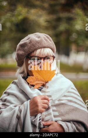 Beauty romantic blonde woman enjoying nature holding leaves in hands outdoors Stock Photo