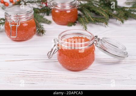 Red caviar in jar on aged white wooden background. Main dish New Year Stock Photo