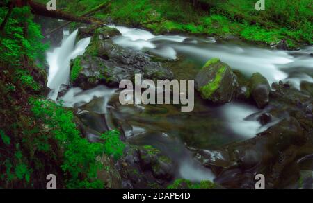 Long exposure of a serene waterfall in a green mossy rainforest Stock Photo