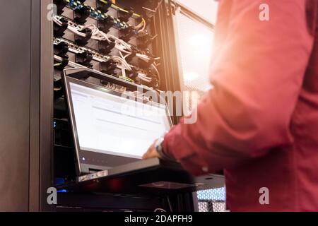 Young it engeneer business man with thin modern aluminium laptop in network server room. Young it engeneer in datacenter server room Stock Photo