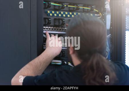 Young it engeneer business man with thin modern aluminium laptop in network server room. Young it engeneer in datacenter server room Stock Photo