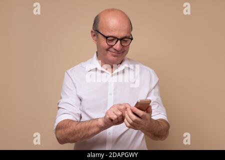 Mature man reading an sms or text message on his mobile Stock Photo