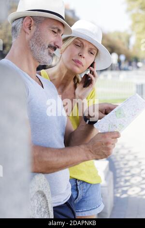 couple of tourists consulting a paper guide in the street Stock Photo