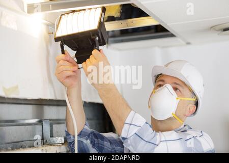electrician man checking the state of the ceiling Stock Photo