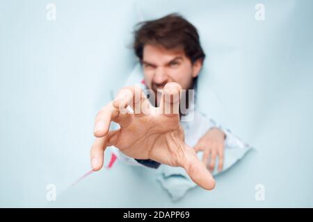Emotional man stretches his hand forward looking through the wall of emotions office Stock Photo