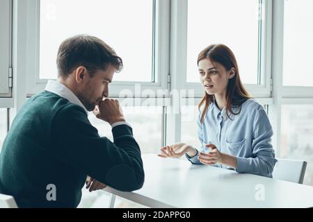 employee upset man and surprised woman at table indoors work  Stock Photo