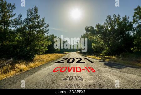 Happy New Year 2021 concept. Asphalt road in forest. Sun shines over empty road in countryside leading to distant through trees in spring or autumn. Stock Photo
