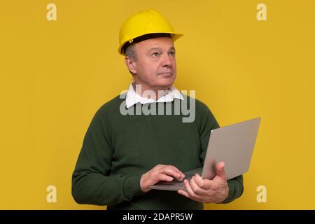Senior foreman with special hard hat working using laptop. Stock Photo