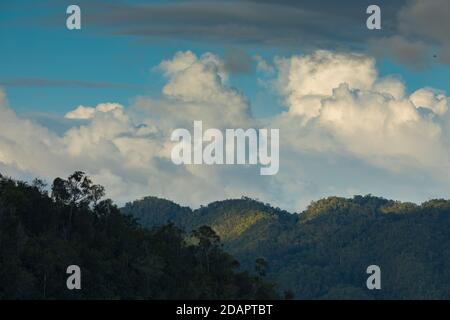 Beautiful clouds and sunset, over the mountains of Waiego Island, covered by thick tropical jungle, in the exotic Raja Ampat Islands, Indonesia, South Stock Photo