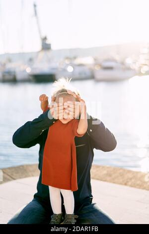 Father and daughter are playing peek-a-boo in a marina in Montenegro Stock Photo