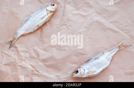 Dried fishes flat lay template banner on craft paper background with empty space for text. Horizontal salted roach cover backdrop. Seafood snack poster, flyer design. Fish frame promotion shop. Stock Photo