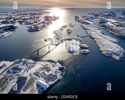 Aerial view, country road with bridge over the sea connects populated, small, winterly islands with the mainland, behind mountains, Heroy, Nordland Stock Photo