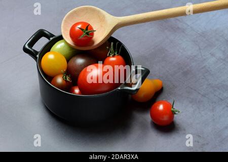 Different cherry tomatoes in pot with cooking spoon, Germany Stock Photo