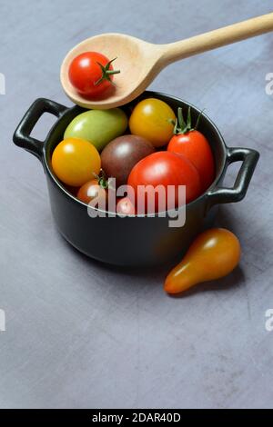 Different cherry tomatoes in pot with cooking spoon, Germany Stock Photo
