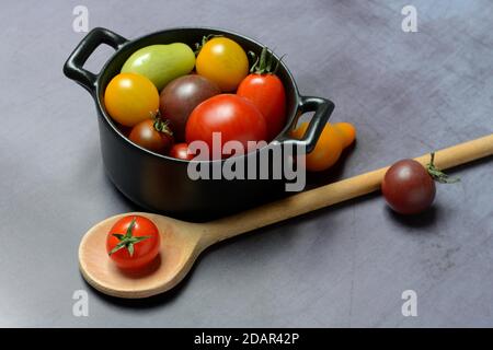 Different cherry tomatoes in pot with cooking spoon, Germany Stock Photo