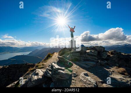 Hiker stretches out his arms in the air, summit of Ben Lomond, view of Lake Wakatipu, Southern Alps, Otago, South Island, New Zealand Stock Photo