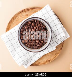 Arabica coffee beans in a ceramic bowl on a wooden tray. Square photo for coffee shops and coffee shops.