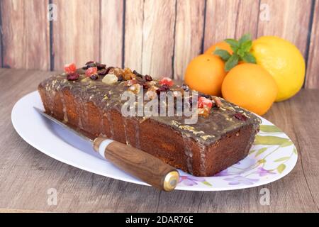Homemade lemon and orange pudding with fruits on a white platter with vintage-style flower drawings on a wooden table, some citrus fruits and a rustic Stock Photo