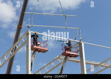 Two construction workers on working platforms, assembling the roof structure of a logistics hall, Duisburg, North Rhine-Westphalia, Germany Stock Photo
